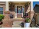 Inviting front porch with brick columns, decorative wreath on the door, and potted plants adding a welcoming touch at 7933 Heathmore Dr, Fairburn, GA 30213