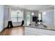 Kitchen with granite island, white cabinets, hardwood floors and pendant lighting with access to the backyard at 7933 Heathmore Dr, Fairburn, GA 30213