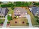 Aerial view of a brick home with manicured lawn, mature landscaping, and a long drive in a suburban neighborhood at 1074 Nash Springs Cir, Lilburn, GA 30047