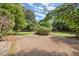 Spacious backyard area with gravel and a partial iron fence, surrounded by mature trees at 3818 Sweet Bottom Dr, Duluth, GA 30096