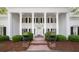 Elegant home entrance with white columns, black shutters, and manicured landscaping at 3818 Sweet Bottom Dr, Duluth, GA 30096