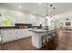 Open kitchen with center island, seating, stainless appliances, with adjacent living space and hardwood floors at 3818 Sweet Bottom Dr, Duluth, GA 30096