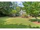 Expansive green yard with mature trees and partial iron fencing surrounding a white home in the background at 3818 Sweet Bottom Dr, Duluth, GA 30096