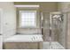 Bright bathroom featuring a soaking tub, walk-in shower with glass door, and tiled walls at 1563 Country Wood Dr, Hoschton, GA 30548