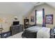 Cozy carpeted bedroom features a sloped ceiling, natural light, and entertainment area with desk and television at 1563 Country Wood Dr, Hoschton, GA 30548