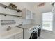 Laundry room featuring newer appliances, white cabinets, utility sink and granite countertop at 1563 Country Wood Dr, Hoschton, GA 30548