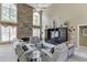 Cozy living room with a stone fireplace, tall windows, and comfortable seating arrangement at 1563 Country Wood Dr, Hoschton, GA 30548