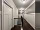 Well-lit hallway with dark hardwood floors, white wainscoting, and a staircase leading to the upper level at 2506 Monta Vista Way, Hoschton, GA 30548