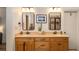 Bathroom featuring double sink vanity with wood cabinets, decorative mirrors, and tile flooring at 374 Beaumont Farms Dr, Sharpsburg, GA 30277