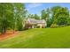 Charming home with well-manicured front yard featuring lush green grass, landscaping, and mature trees at 374 Beaumont Farms Dr, Sharpsburg, GA 30277