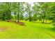 Expansive backyard featuring lush greenery, mature trees, landscaped flowerbeds, and a tranquil stream at 201 Smithstone Path, Fayetteville, GA 30214