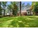 Expansive backyard featuring a lush lawn, brick patio, outdoor fireplace, and mature trees at 4105 Peachtree Dunwoody Ne Rd, Atlanta, GA 30342