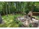 Lush backyard featuring a stone patio with an outdoor fireplace and dining area, perfect for relaxing and entertaining guests at 4105 Peachtree Dunwoody Ne Rd, Atlanta, GA 30342