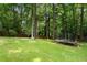 Spacious backyard with lush green grass and mature trees, featuring a trampoline for recreation and outdoor enjoyment at 4105 Peachtree Dunwoody Ne Rd, Atlanta, GA 30342