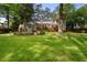 Expansive backyard featuring a deck, stone patio with outdoor fireplace, and lush greenery, perfect for entertaining and relaxation at 4105 Peachtree Dunwoody Ne Rd, Atlanta, GA 30342