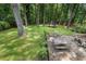 Serene backyard with a stone patio featuring a dining area, surrounded by lush greenery, a trampoline, and mature trees at 4105 Peachtree Dunwoody Ne Rd, Atlanta, GA 30342