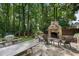 Stone patio with a cozy outdoor fireplace, comfortable seating, and a view of the lush backyard with a trampoline at 4105 Peachtree Dunwoody Ne Rd, Atlanta, GA 30342