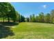 Expansive lawn view with lush greenery surrounded by beautiful trees and blue skies at 7120 Lullwater Rd, Cumming, GA 30040