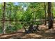 Serene pond view with chairs on a grassy lawn surrounded by a beautiful forest at 7120 Lullwater Rd, Cumming, GA 30040