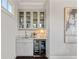 Stylish wet bar with granite countertops, a wine fridge, and glass-front cabinets at 7120 Lullwater Rd, Cumming, GA 30040