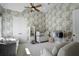 Bedroom with patterned wallpaper, ceiling fan, crib, and sitting area at 3888 Peachtree Dunwoody Rd, Atlanta, GA 30342