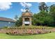 Inviting community entrance with stone signage, colorful flowers, and manicured landscaping at 655 Grove Manor Ct, Suwanee, GA 30024