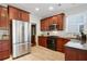 Well-equipped kitchen with stainless steel refrigerator, gas range, and rich wood cabinetry at 655 Grove Manor Ct, Suwanee, GA 30024