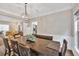 A formal dining room with decorative lighting and wooden table adjacent to living room at 1500 Highland Farm Dr, Suwanee, GA 30024