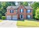 A two-story brick home with a well-manicured lawn, mature trees, and a two-car garage at 1500 Highland Farm Dr, Suwanee, GA 30024