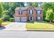 A two-story brick home with a well-manicured lawn, mature trees, and a two-car garage at 1500 Highland Farm Dr, Suwanee, GA 30024