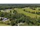 Aerial view of a house nestled amongst trees near green pastures, showcasing the rural setting at 200 Mcclure Dr, Cumming, GA 30028