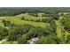 Expansive aerial view of land, trees, and fields with a residence nestled in the trees at 200 Mcclure Dr, Cumming, GA 30028