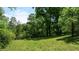 A private backyard featuring a lush green lawn surrounded by mature trees and natural landscaping at 200 Mcclure Dr, Cumming, GA 30028