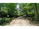 Long gravel driveway over a small bridge through lush greenery at 200 Mcclure Dr, Cumming, GA 30028