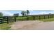 Black wooden fence and gated entrance with a horse barn in the background at 200 Mcclure Dr, Cumming, GA 30028