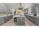 Spacious kitchen with gray cabinets, island with cooktop and seating, stainless appliances, and tile backsplash at 200 Mcclure Dr, Cumming, GA 30028
