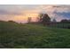 Scenic sunset view of horse grazing in a lush green pasture with split rail fencing at 200 Mcclure Dr, Cumming, GA 30028