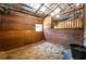 Horse stall with wood paneling, hay on the floor, barred window, and a black water bucket at 200 Mcclure Dr, Cumming, GA 30028