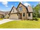 Attractive home featuring stone and stucco accents, a multi-car garage, and a green lawn at 208 Regester Way, Peachtree City, GA 30269