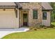 Charming front entrance with stone accents, a wooden door, and a well-maintained lawn at 208 Regester Way, Peachtree City, GA 30269