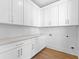 Bright laundry room with white cabinetry, countertop, and hardwood floors at 208 Regester Way, Peachtree City, GA 30269
