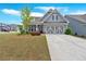 Well-maintained lawn leads to a charming grey home with a two-car garage and inviting front entrance at 427 Bluffs View Ln, Canton, GA 30114