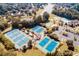 Aerial view showcasing tennis courts, a pool, parking, and a lake in a beautifully landscaped community at 1739 Praters Pt, Dacula, GA 30019