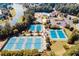 Aerial view showing a complex of tennis courts along with parking, a lake, and an outdoor pool at 1739 Praters Pt, Dacula, GA 30019