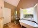 Bright bathroom featuring a standalone tub, glass shower, and large window with shuttered blinds at 1739 Praters Pt, Dacula, GA 30019