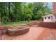 Large patio area with brick firepit and steps up to the house, surrounded by lush greenery at 2655 Hayden Dr, East Point, GA 30344