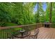 A peaceful, wooded view from the outdoor deck with a metal dining table and grill at 3370 Ashton Dr, Suwanee, GA 30024