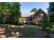 Backyard of brick home with a covered porch, mature trees, and well-maintained lawn at 1210 Lancelot Ct, Loganville, GA 30052