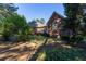 Backyard view of brick home, featuring a deck, lush landscaping, and mature trees for privacy at 1210 Lancelot Ct, Loganville, GA 30052