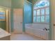Bright bathroom with a large tub under an arched window with shuttered blinds at 1210 Lancelot Ct, Loganville, GA 30052